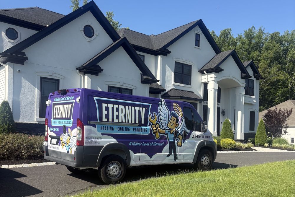 Eternity van parked outside a modern house, promoting heating, cooling, and plumbing services.